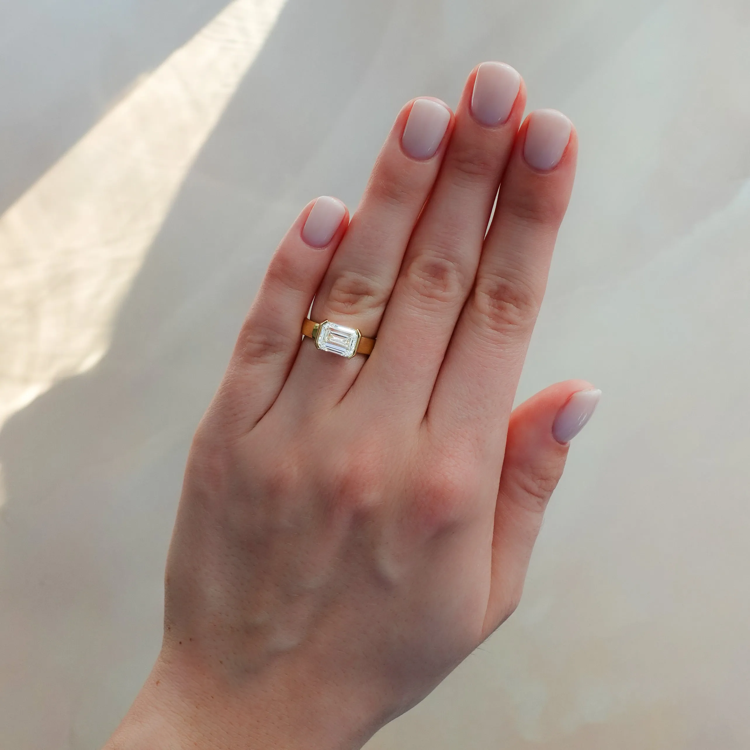 Finest Half Bezel Solitaire Engagement Ring With East West Emerald Cut Diamond
